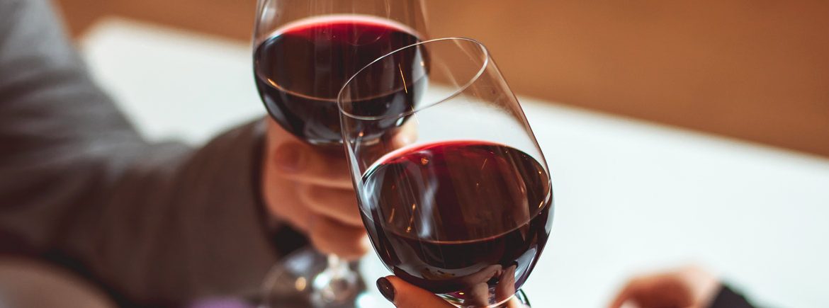 Un uomo e una donna brindano con un calice di vino rosso