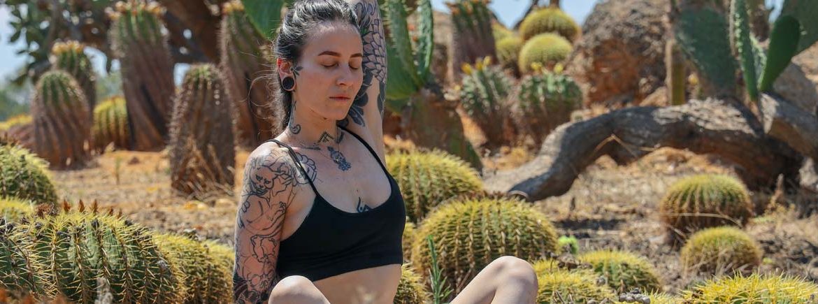 Una ragazza fa yoga in mezzo ai cactus